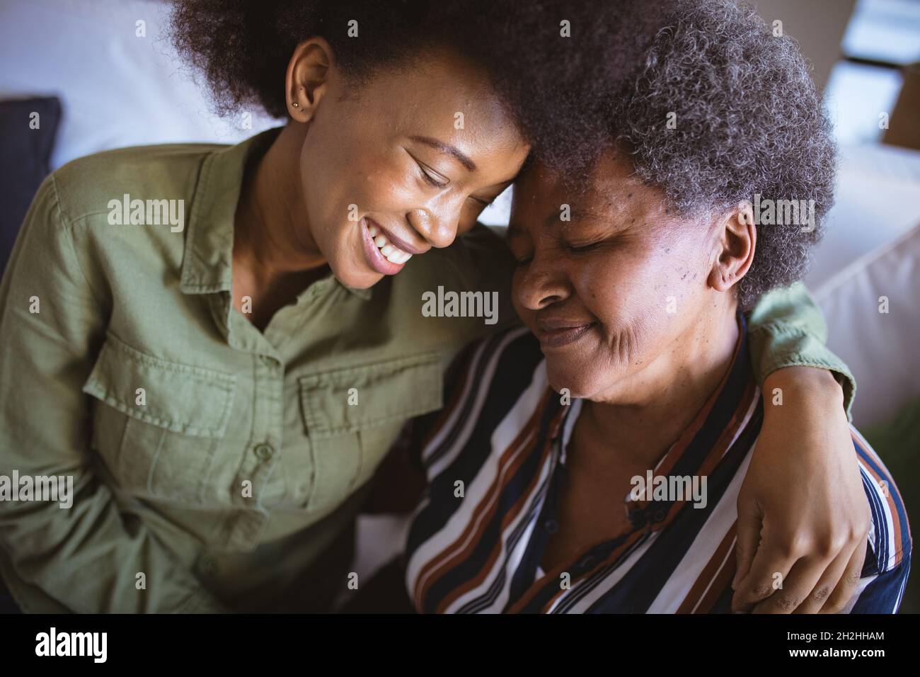 Femme aînée afro-américaine souriante avec une fille adulte embrassant avec les yeux fermés Banque D'Images