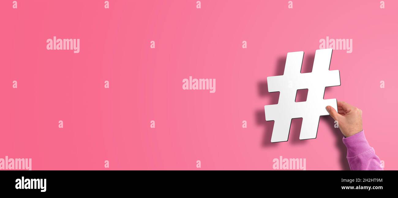 main tenant le symbole de hachage, hashtag sur fond rose, concept de médias sociaux avec espace de copie Banque D'Images