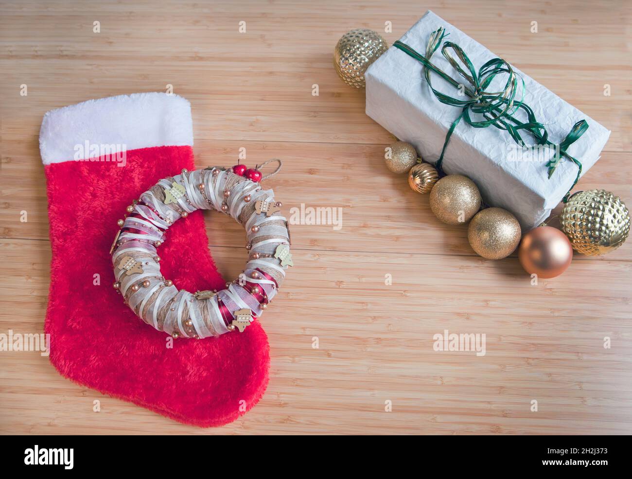 Chaussette rouge pour cadeaux de Noël, cadeau emballé sur papier recyclé, décorations de boules dorées sur table. Banque D'Images