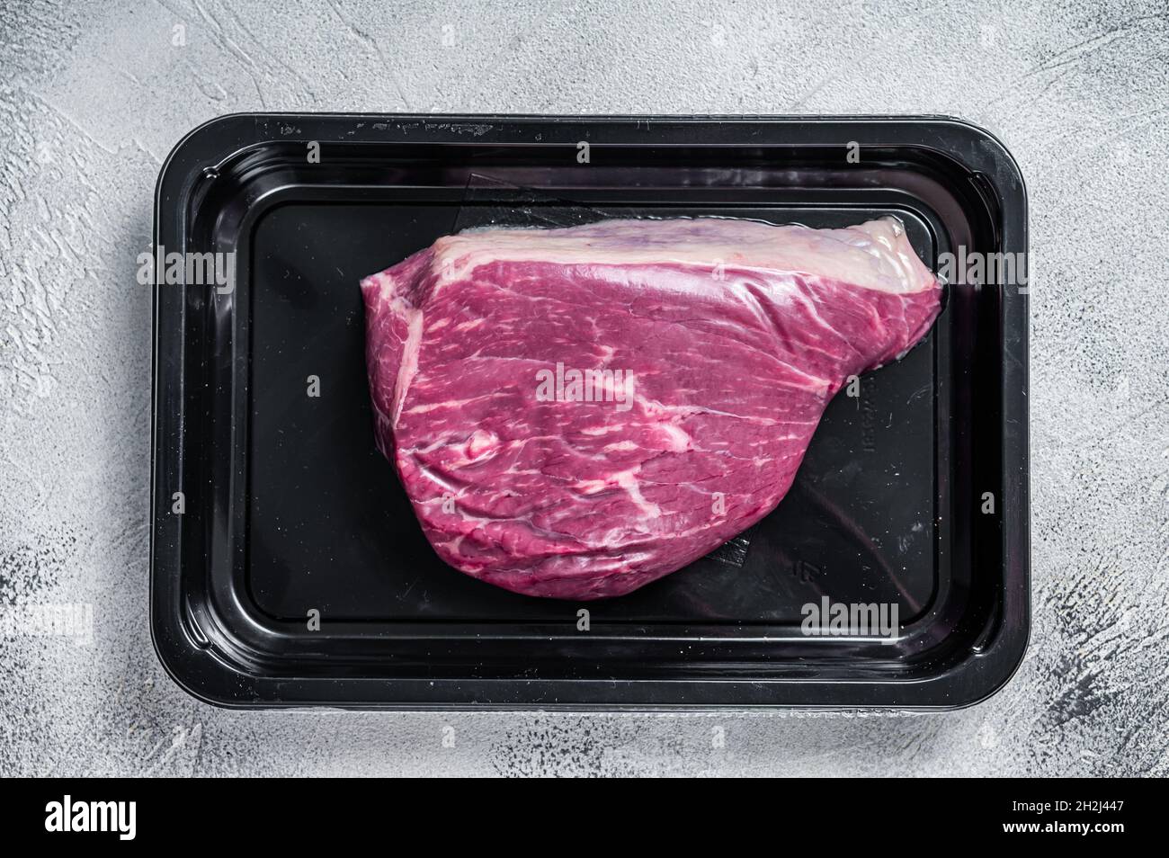 Steak de bœuf cru ou steak de viande de bœuf au sirloin dans un emballage sous vide. Arrière-plan blanc. Vue de dessus Banque D'Images