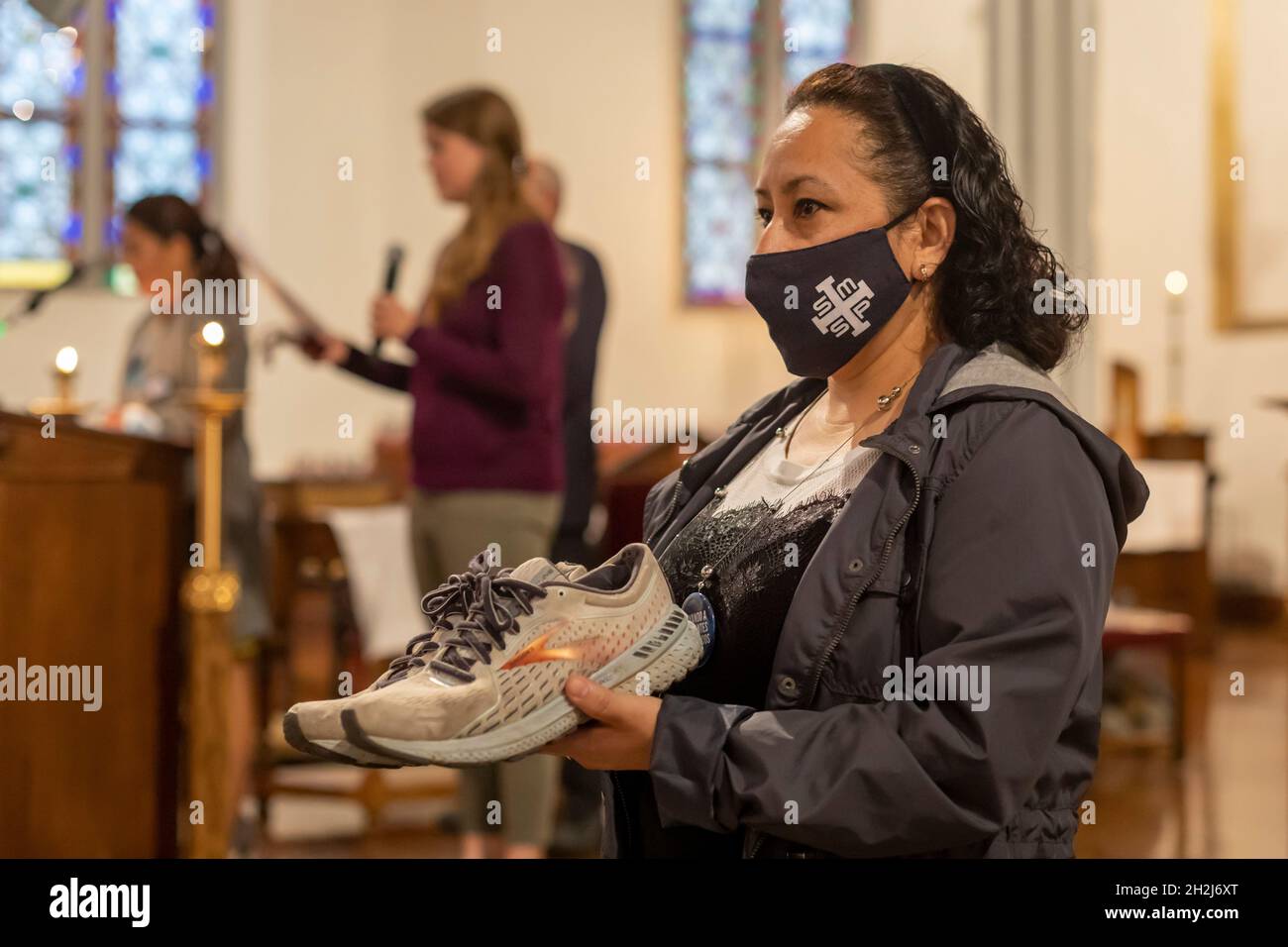 Detroit, Michigan - pendant la messe de la plupart des églises catholiques de la Sainte-Trinité, Nancy Juarez tient les chaussures qu'un réfugié portait lorsqu'elle voyage du Guatemala Banque D'Images