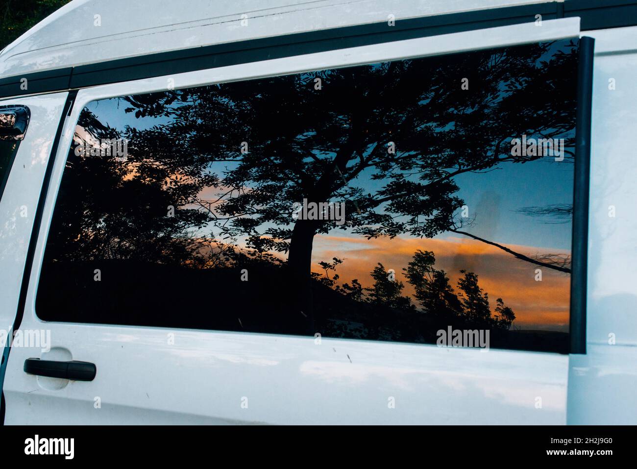 vue du lever du soleil sur le loch se reflète dans la fenêtre d'un camping sauvage de campervan Banque D'Images