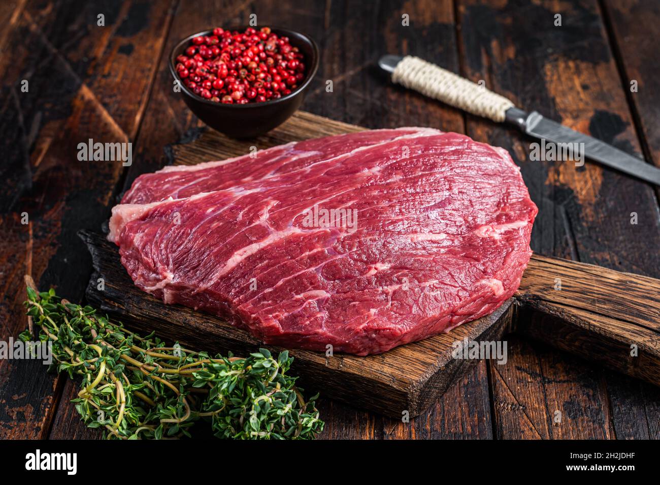 Steak de chapeau de sirloin cru ou steak de Picanha sur une planche de bois au thym. Arrière-plan en bois sombre. Vue de dessus Banque D'Images