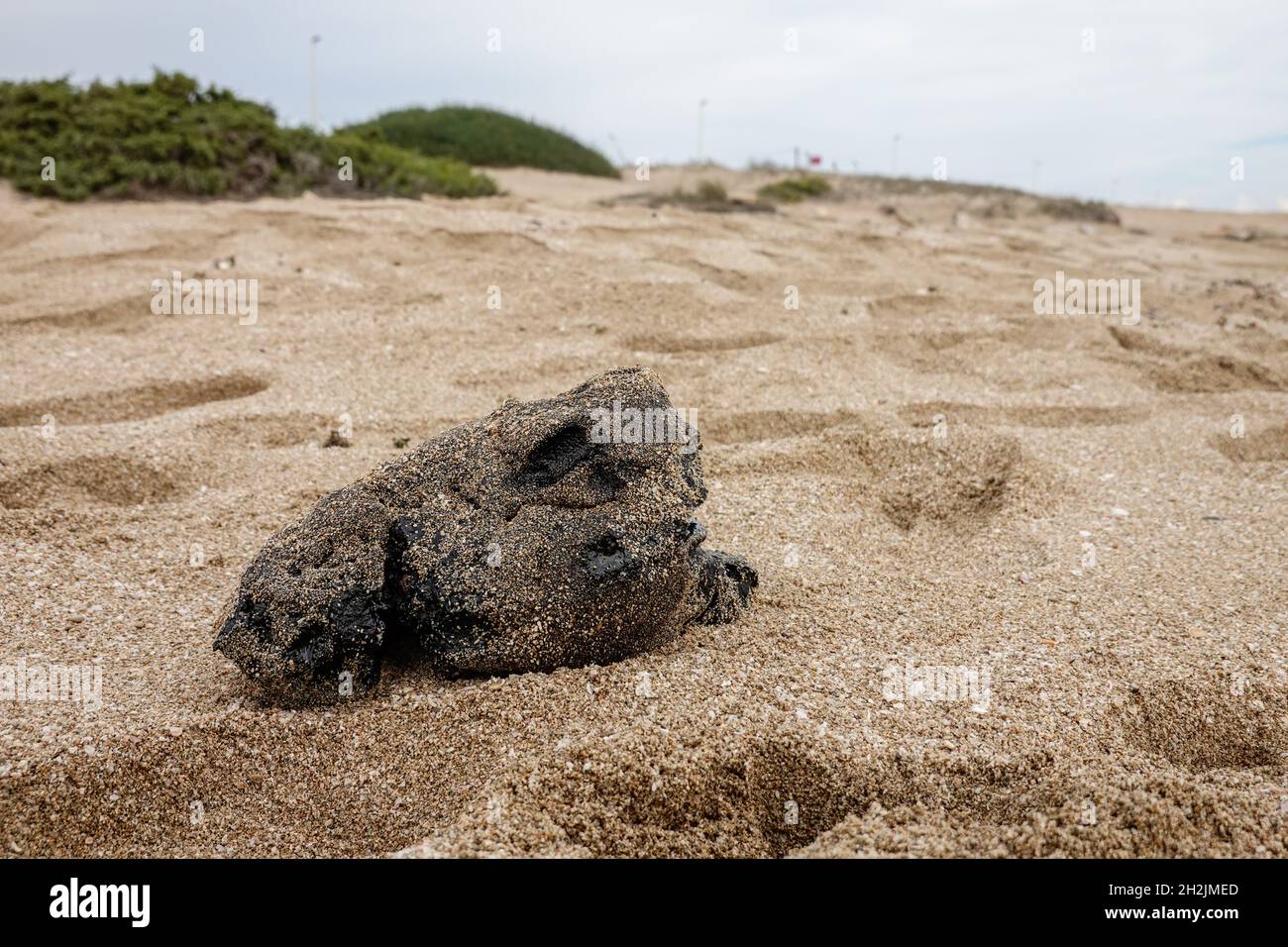 Un bloc de goudron noir sur la plage.Résidus du traitement des hydrocarbures.Il y a un énorme problème écologique dans la mer Méditerranée. Banque D'Images