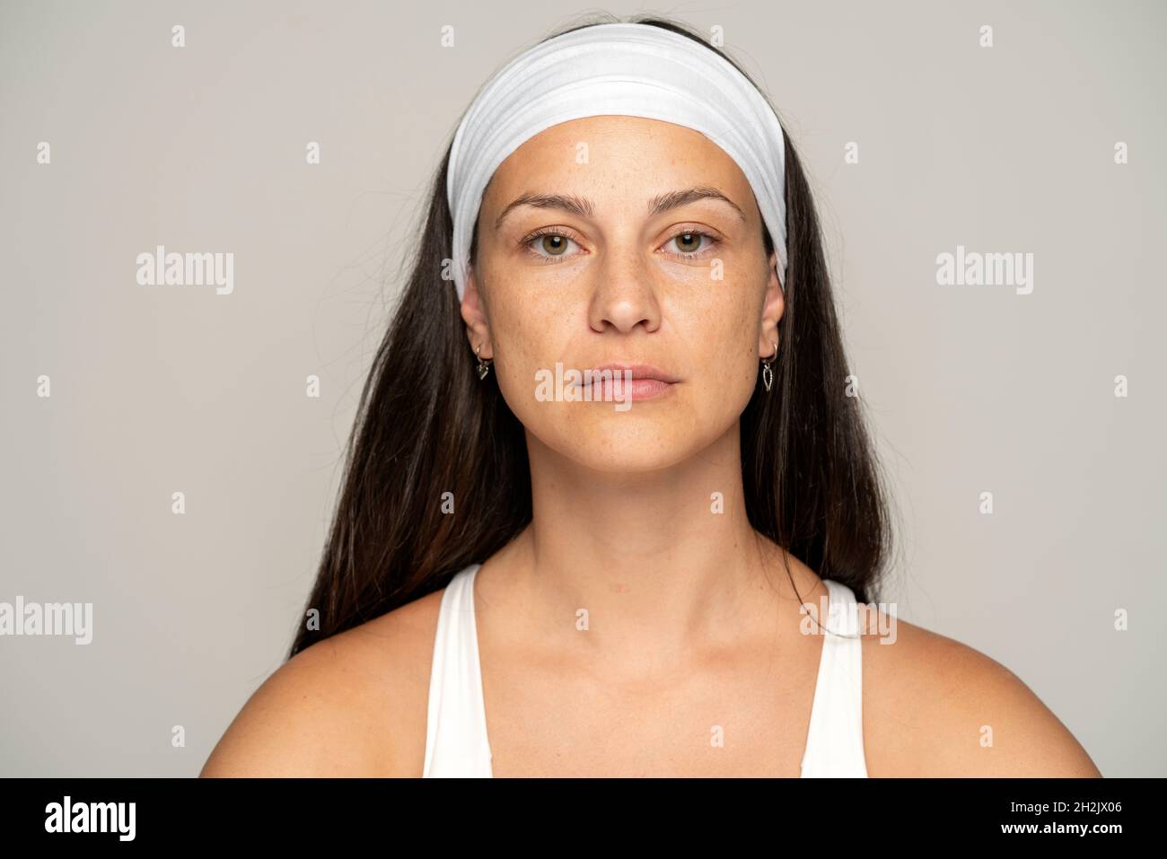 Portrait d'une jeune femme sans maquillage sur fond gris Banque D'Images