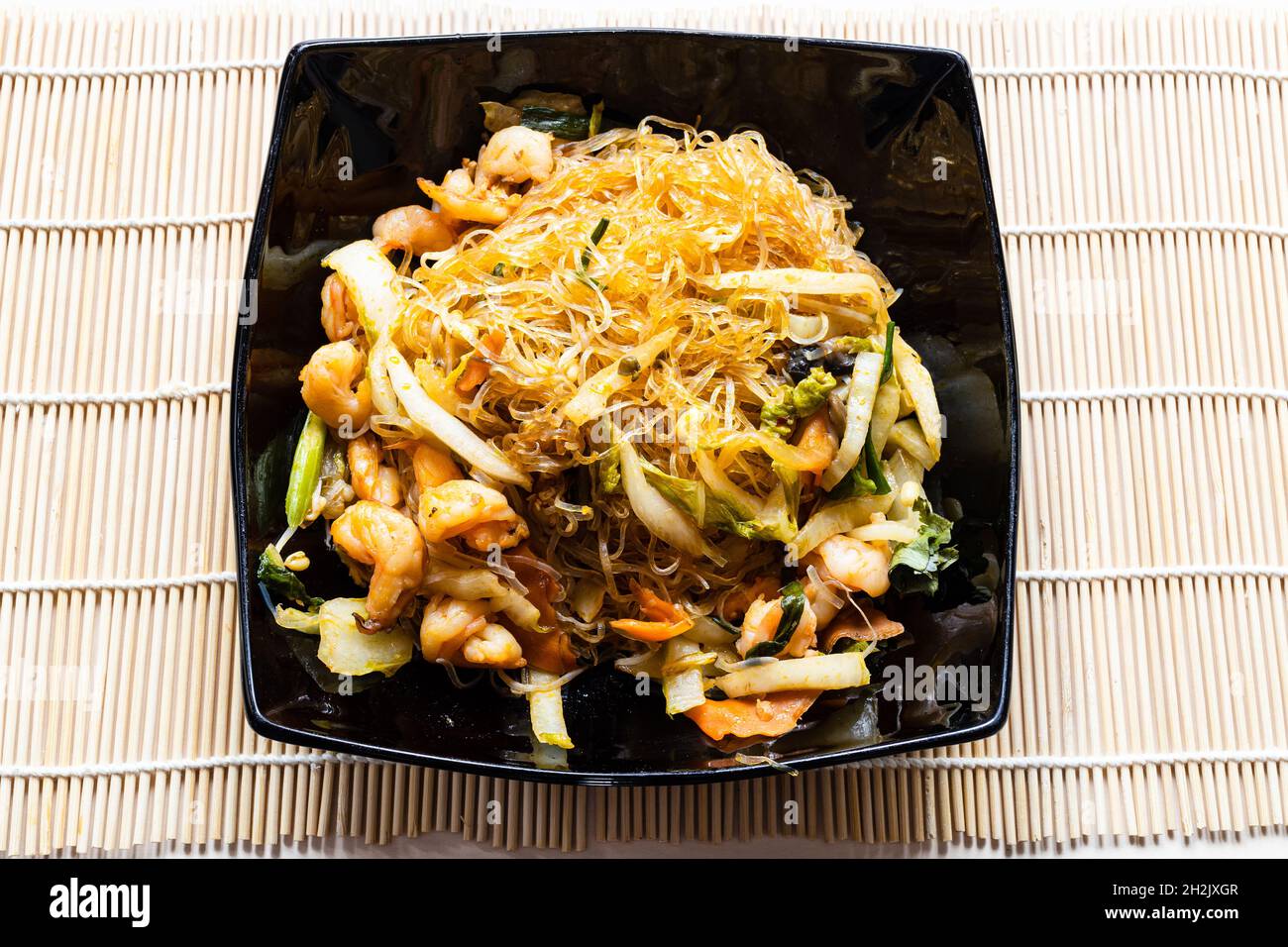 Portion de nouilles en verre sautées au wok vietnamien Mien Xao avec  légumes et crevettes dans un bol noir sur une table en bois Photo Stock -  Alamy
