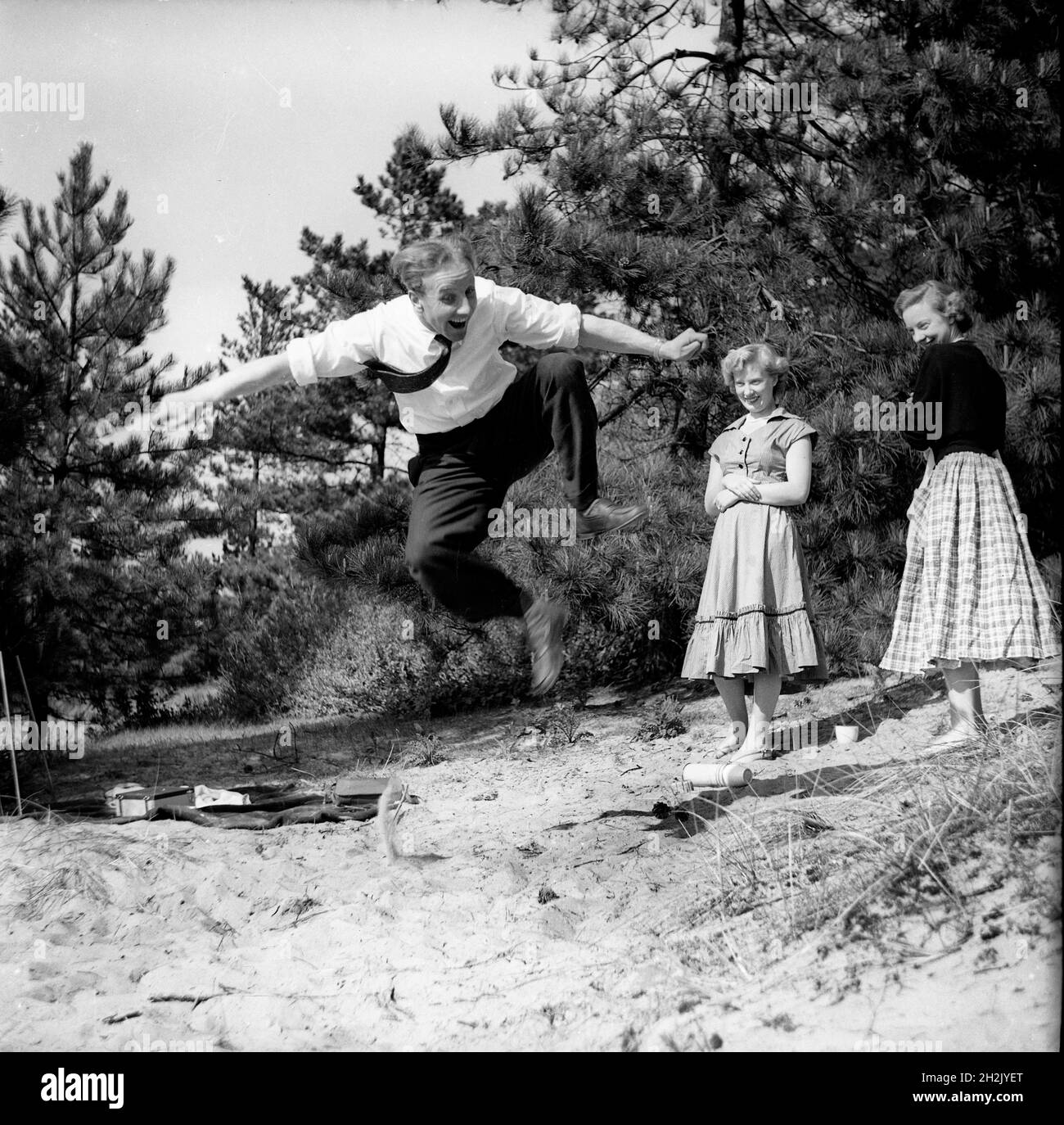 Jeune homme impressant les filles en sautant dans l'air Grande-Bretagne 1950 Banque D'Images