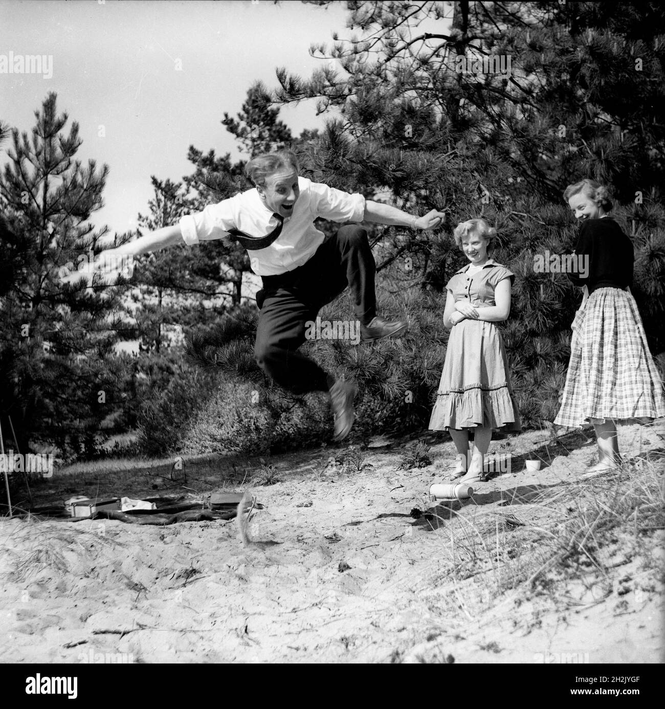 Jeune homme impressant les filles en sautant dans l'air Grande-Bretagne 1950 Banque D'Images