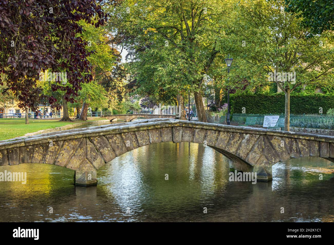 Un pont en pierre voûté traversant la rivière Windrush dans le pittoresque village des Cotswolds de Bourton-on-the-Water, Gloucestershire, Angleterre. Banque D'Images