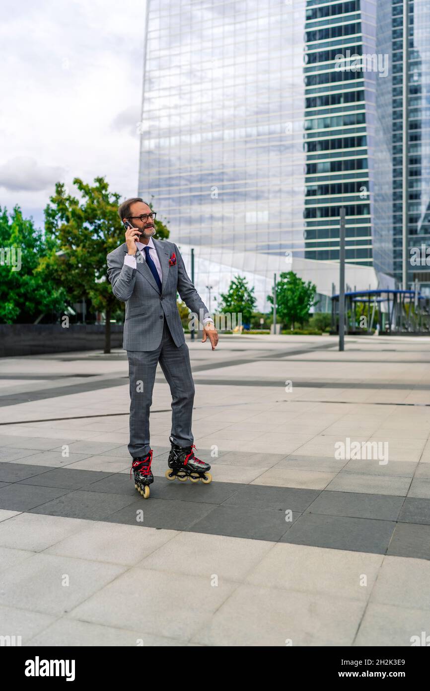 patinage de direction avec ses patins en ligne tout en parlant sur son smartphone Banque D'Images