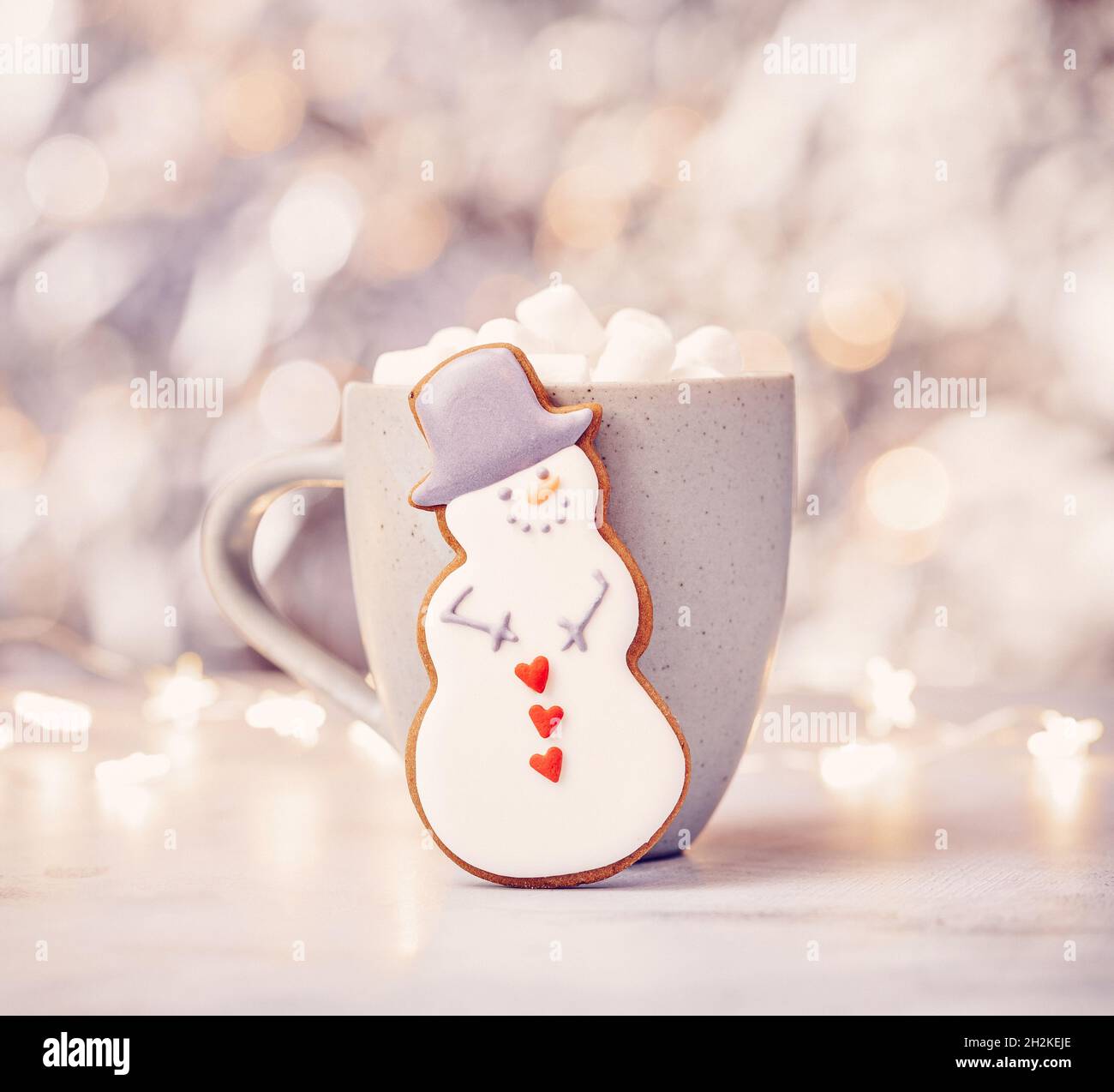 Mignon pain d'épice Snowman cookie devant une tasse de chocolat chaud avec guimauves.Arrière-plan joli bokeh. Banque D'Images
