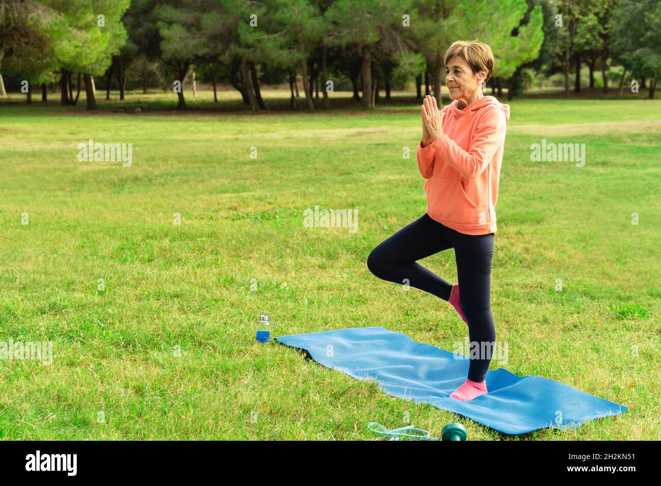 Femme senior faisant de l'entraînement de yoga routine en plein air au parc de la ville - âge et concept de mode de vie sain Banque D'Images