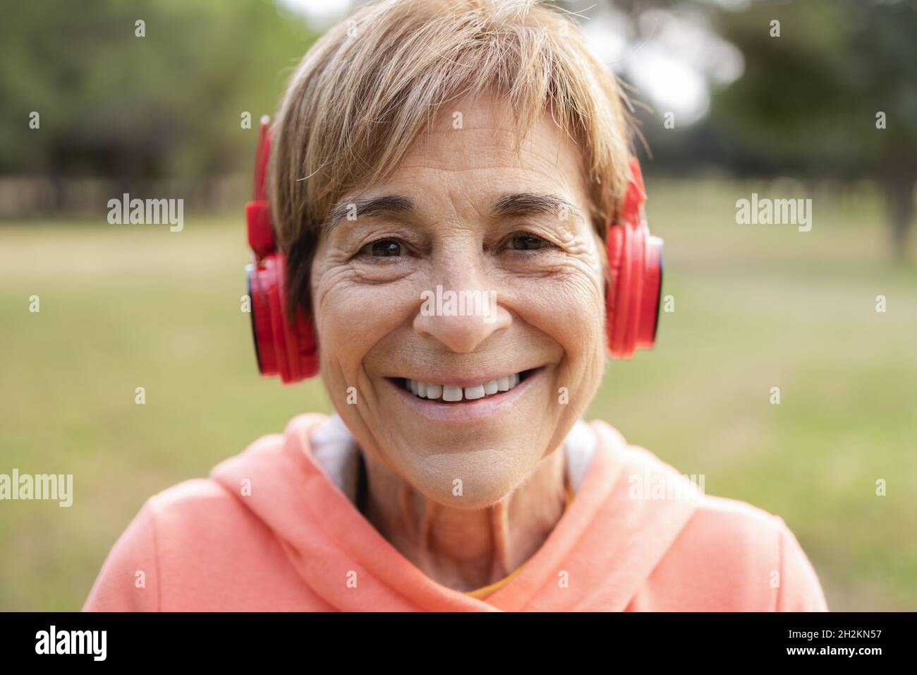 Portrait d'une femme âgée écoutant de la musique de liste de lecture après une routine de jogging en plein air - style de vie sain des personnes âgées Banque D'Images