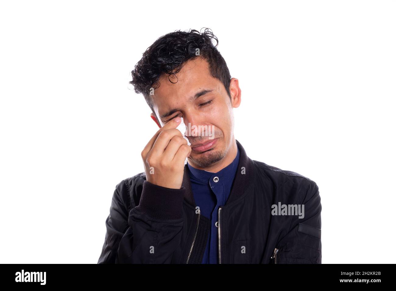 Jeune adulte jeune homme pleure, isolé sur fond blanc.Homme pleurant et essuyant ses larmes avec un mouchoir blanc. Banque D'Images