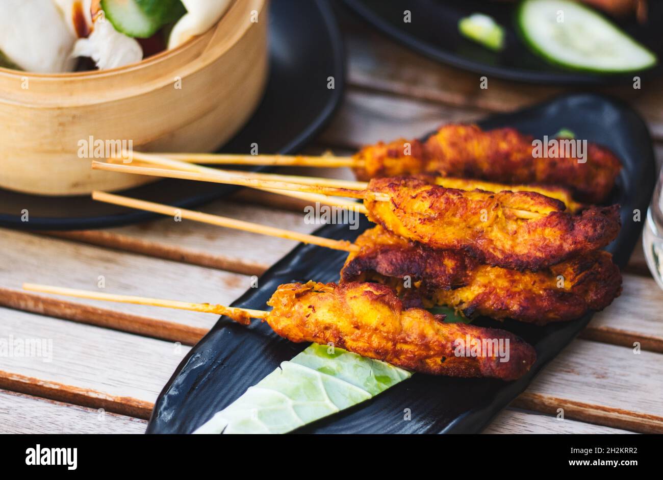 Morceaux de satay de poulet sur des brochettes en bois sur une assiette Banque D'Images