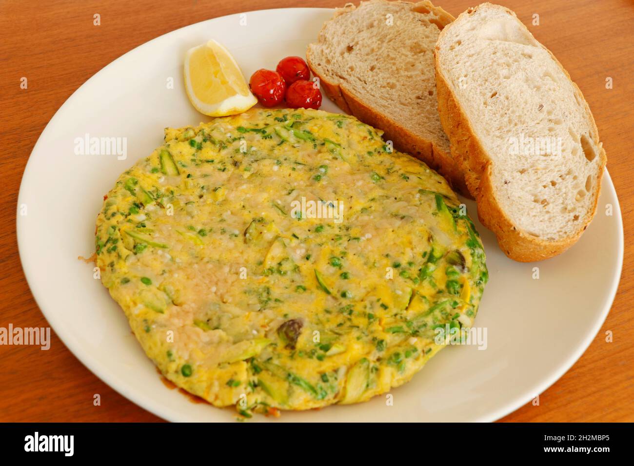 omelette aux œufs bio farcie au fromage, asperges, épinards, feuilles de kale servies avec des tomates et des tranches de pain, petit déjeuner concept food Banque D'Images