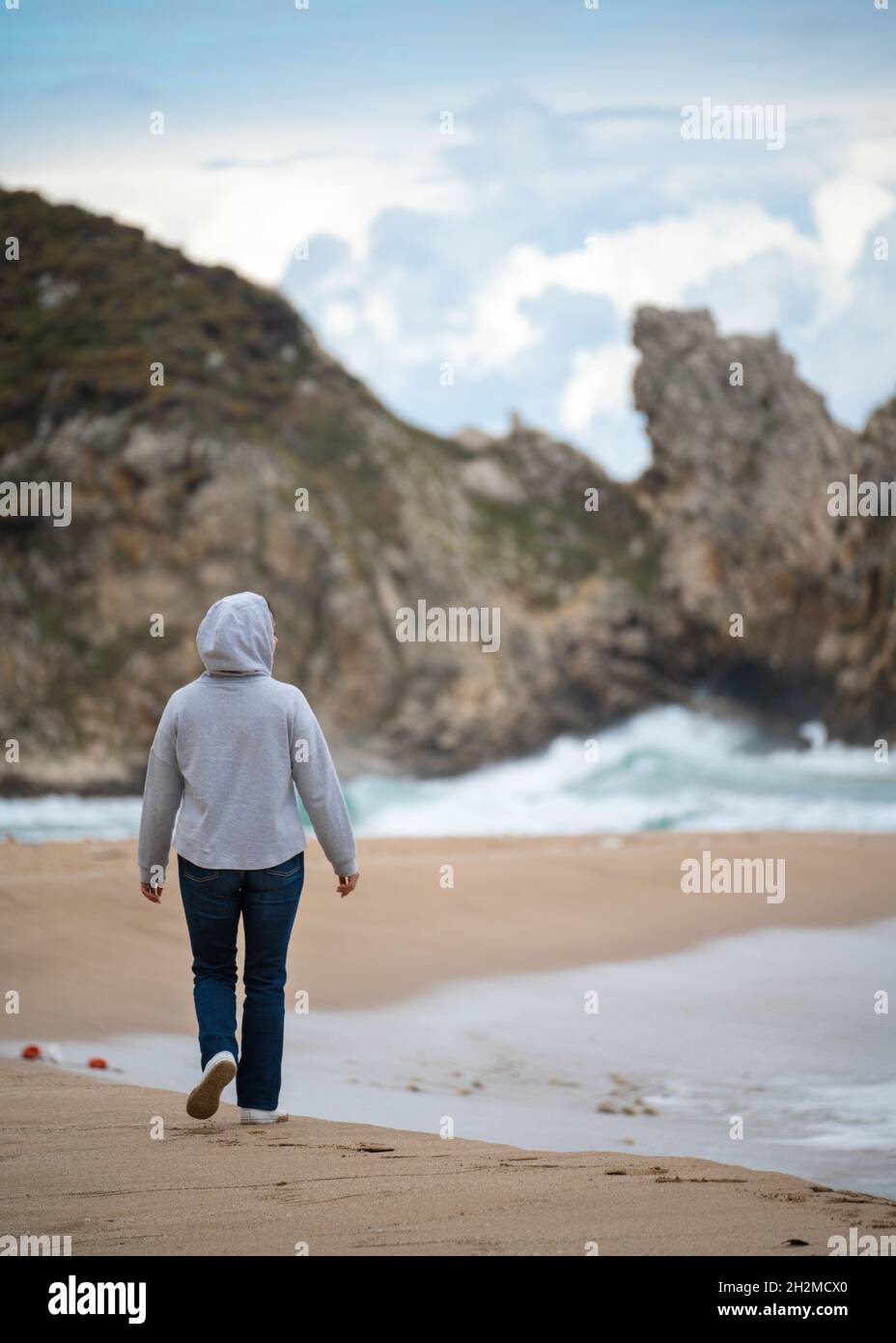 femme d'âge moyen marchant le long de la ligne de l'océan en automne, hiver, vie active. marche le long de la mer par temps frais. côte de californie Banque D'Images