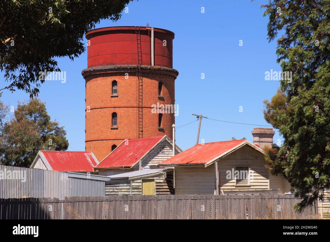 Ancienne tour d'eau de chemin de fer en brique rouge et chalets en panneaux d'intempéries avec rooves en fer ondulé rouge à Warracknabeal, Wimmera Mallee, Victoria, Australie Banque D'Images