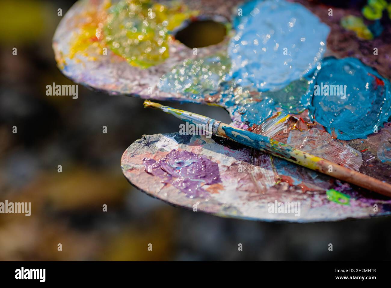 Image de faible profondeur de champ (mise au point sélective) avec une palette de couleurs de peintre tout en peignant un paysage lors d'une journée d'automne ensoleillée. Banque D'Images