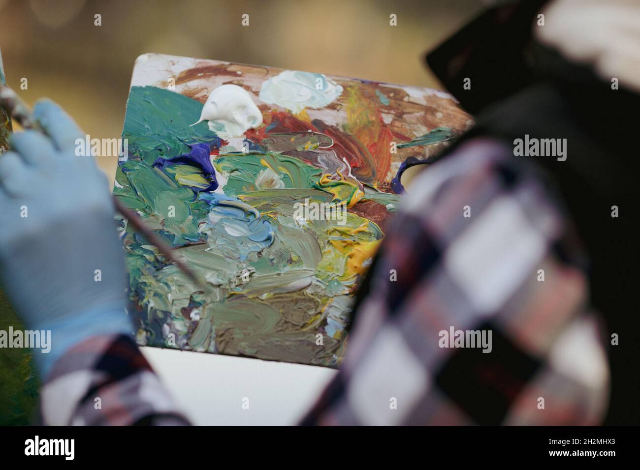 Image de faible profondeur de champ (mise au point sélective) avec la main d'une femme peintre et sa palette de couleurs tout en peignant un paysage sur un da d'automne ensoleillé Banque D'Images
