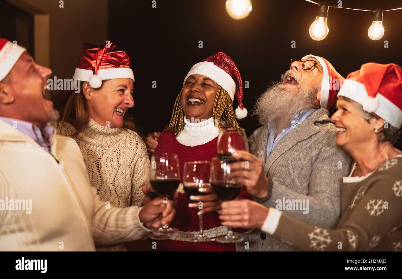 De joyeux amis senior célébrant les vacances de Noël tout en dégustant du rouge verres à vin sur le patio de la maison fête Banque D'Images