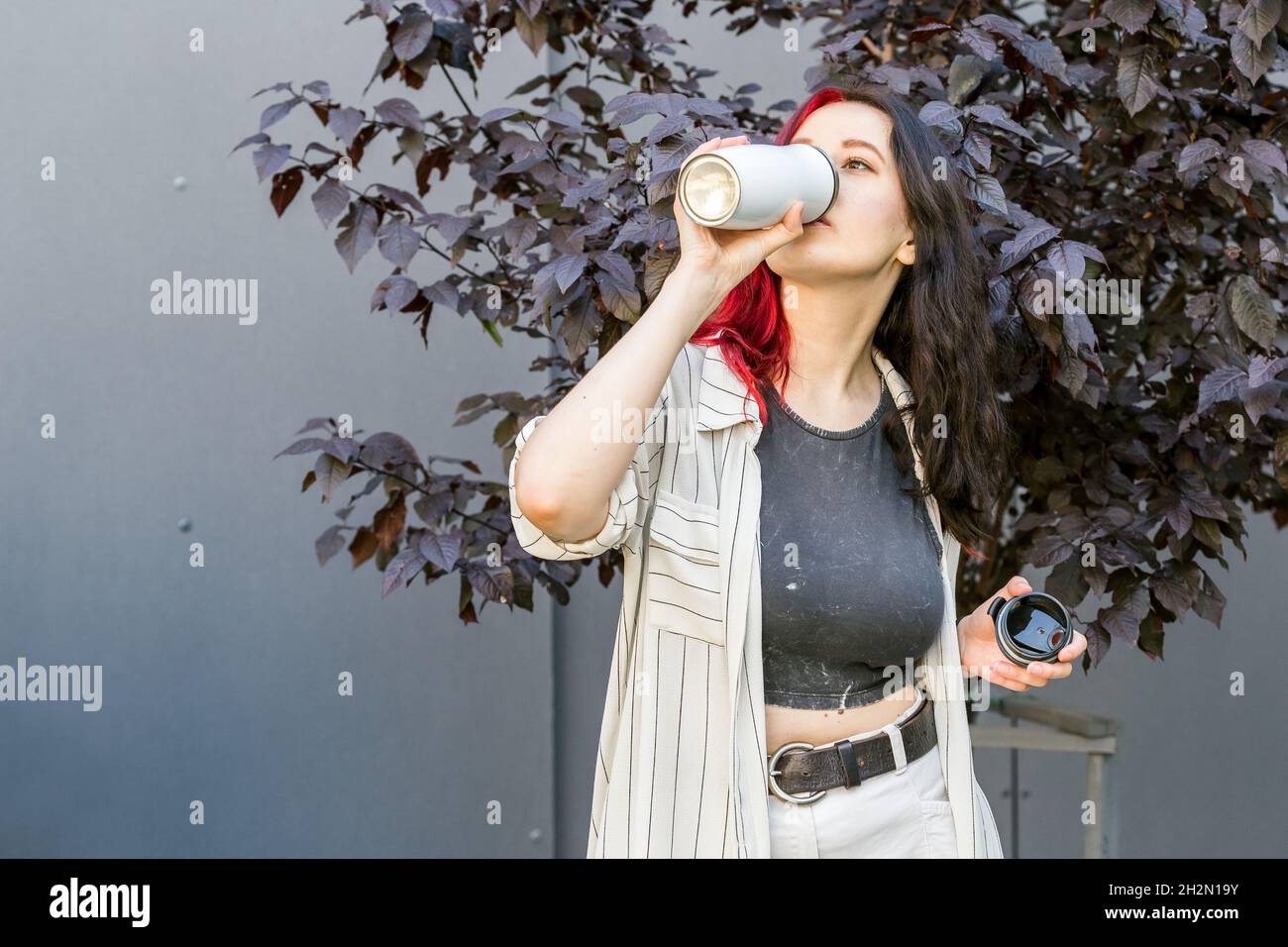 Jeune femme buvant dans le mug isotherme réutilisable.Concept de rester hydraté Banque D'Images