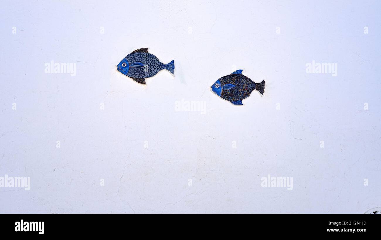deux poissons en céramique bleue sur un mur blanc. espace de copie Banque D'Images