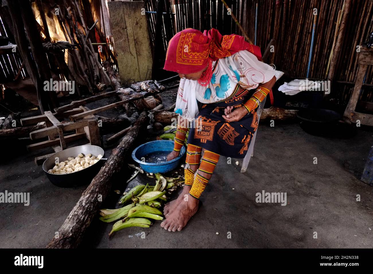 Une femme indigène du peuple Guna portant des perles traditionnelles ornement de jambe lavant des bananes dans sa cuisine de l'île de Carti Sugtupu dans la 'Comarca' (région) des indigènes Guna Yala connu sous le nom de Kuna situé dans l'archipel de San Blas Blas îles dans le nord-est du Panama face à la CaraïbeMer. Banque D'Images