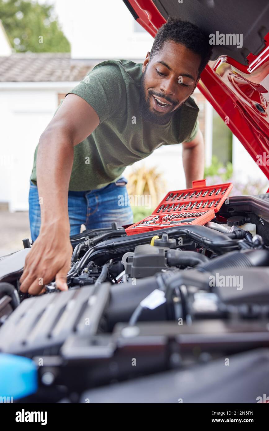 Homme travaillant sous le capot d'une voiture fixant le moteur à l'aide d'une clé Banque D'Images