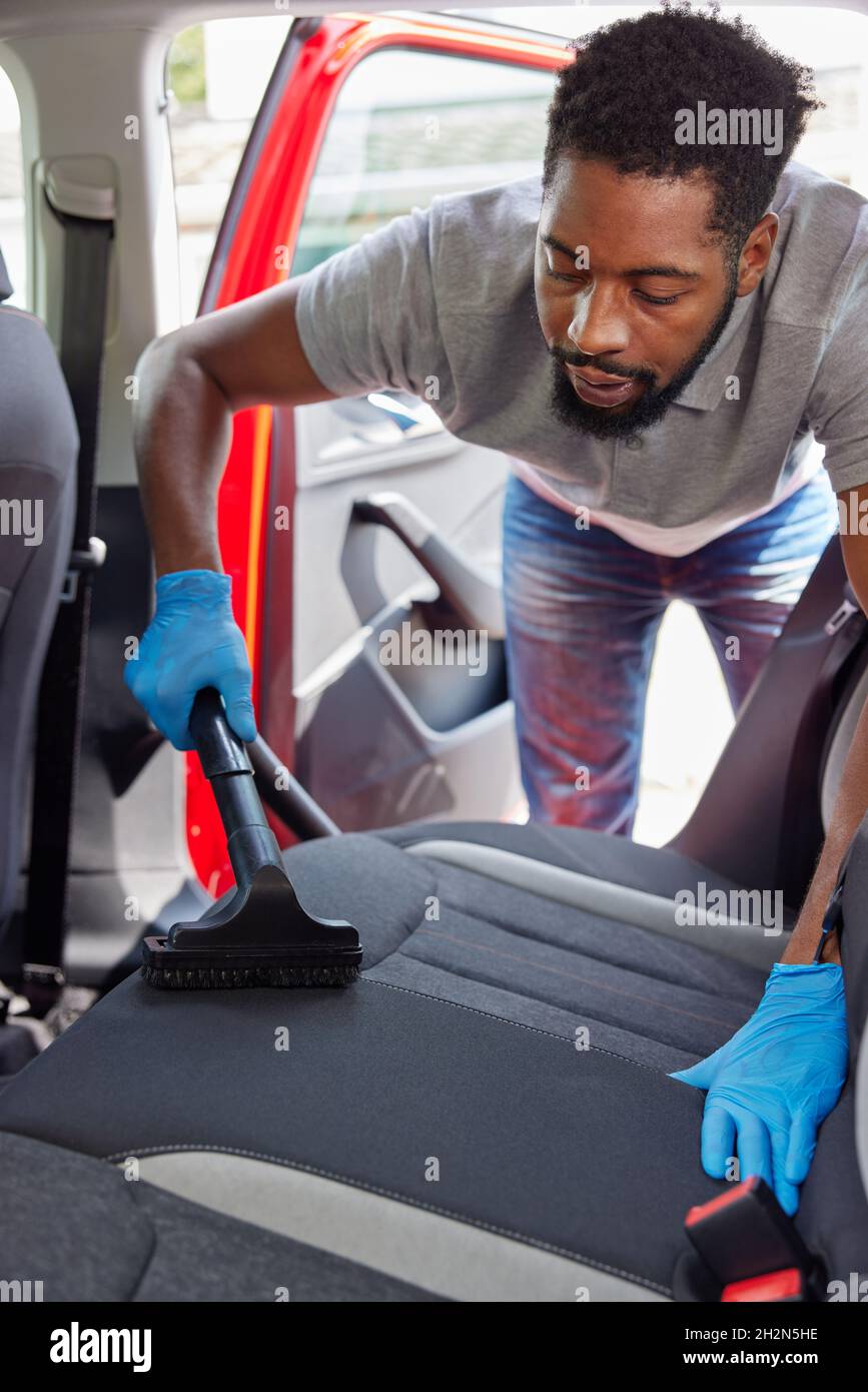 Man Hooering et nettoyage des sièges arrière de voiture pendant le service de voiturier Banque D'Images