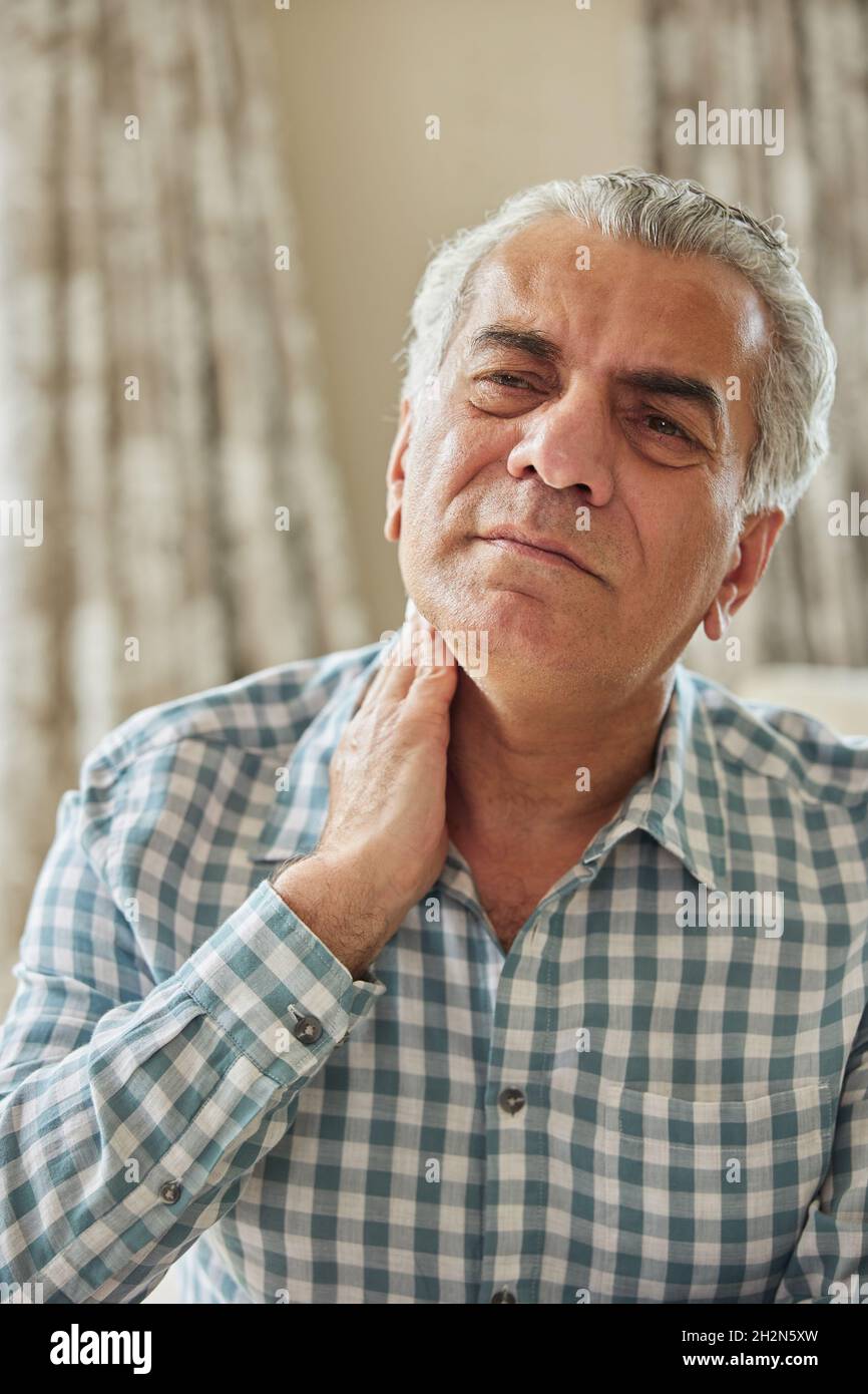 Homme mature à la maison souffrant de douleurs musculaires ou de douleurs dans le cou Banque D'Images