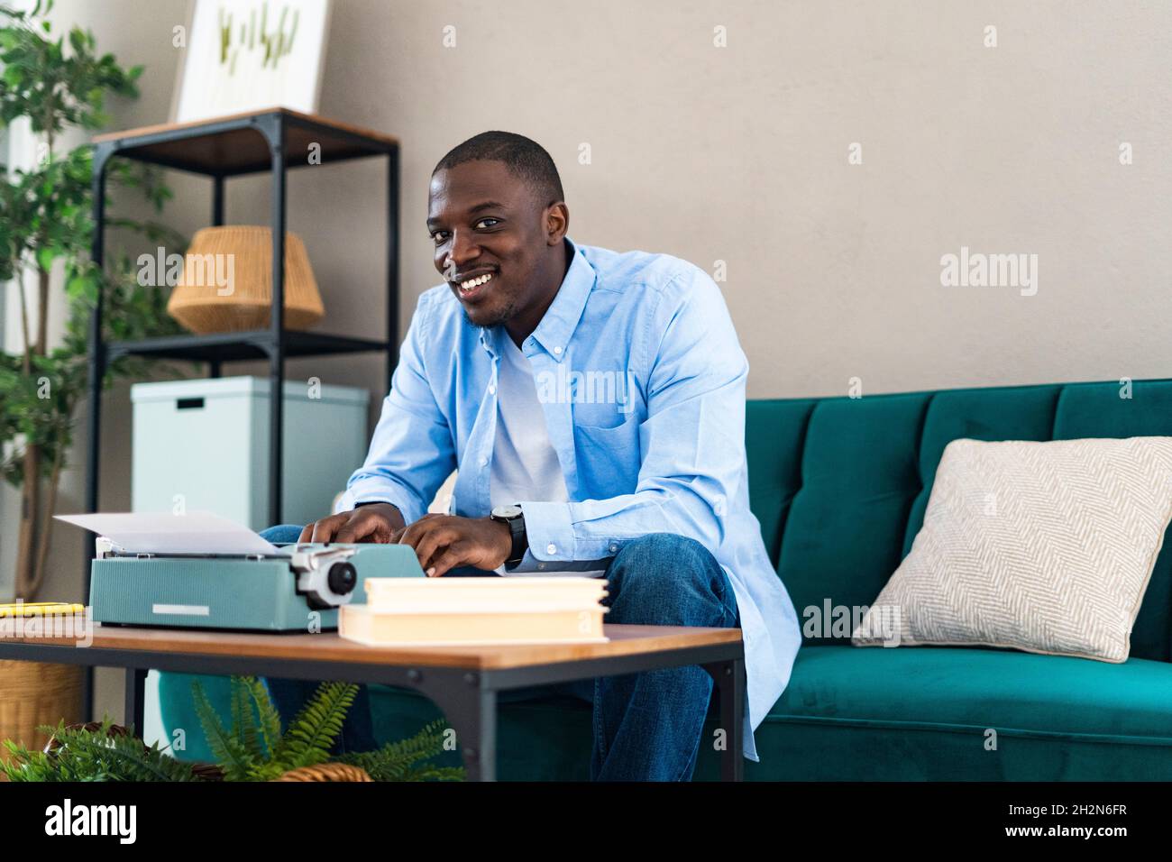 Homme moyen adulte utilisant une vieille machine à écrire sur une table à la maison Banque D'Images