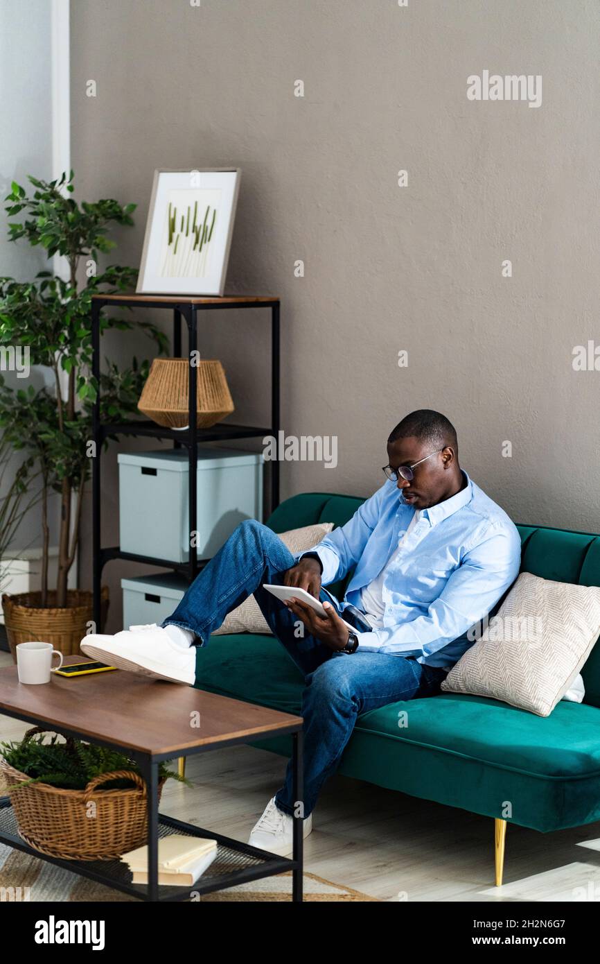 Souriant travailleur indépendant masculin utilisant une tablette numérique tout en travaillant à domicile Banque D'Images