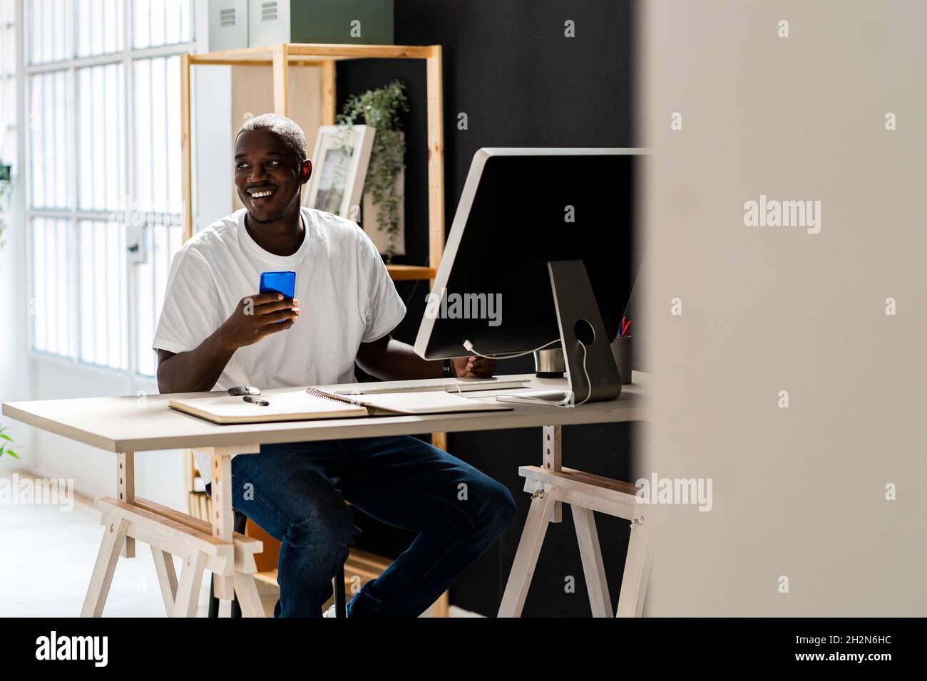 Travailleur indépendant utilisant un smartphone au bureau en studio Banque D'Images