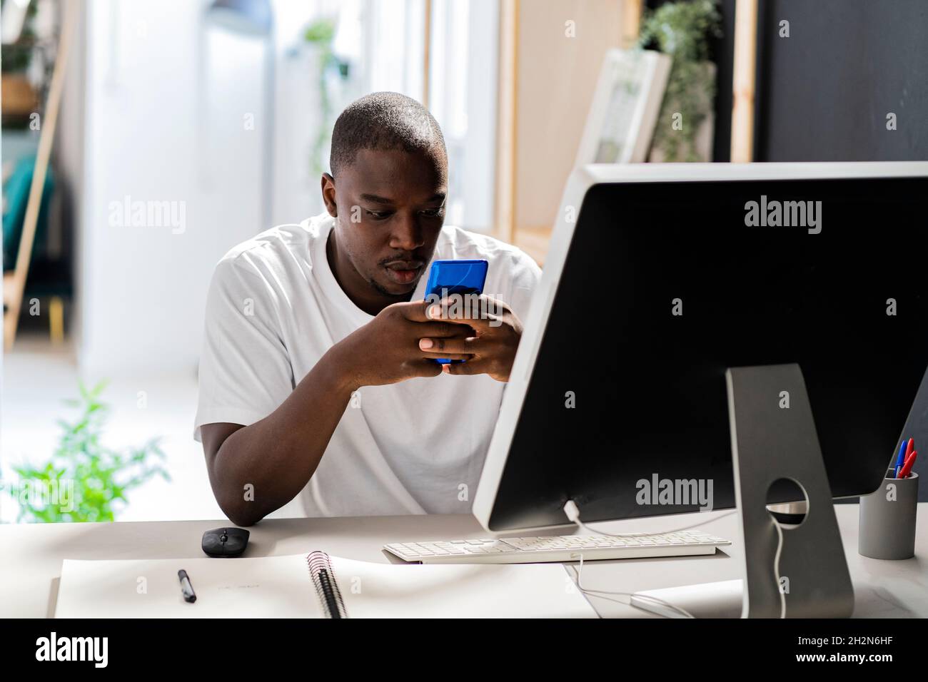 Travailleur indépendant qui touche l'écran du bureau tout en étant assis au bureau en studio Banque D'Images