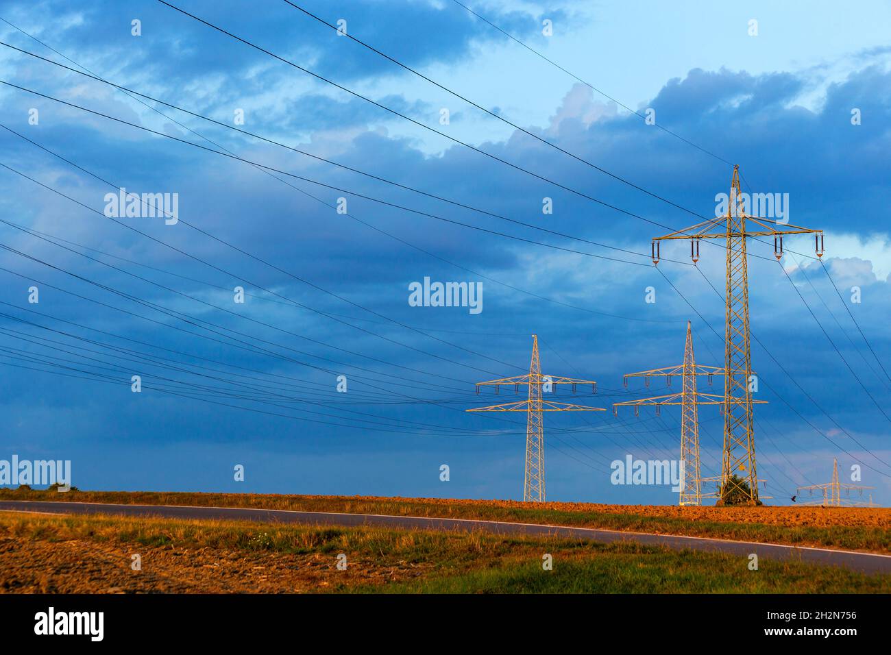 Pylônes d'électricité se tenant contre le ciel bleu nuageux Banque D'Images