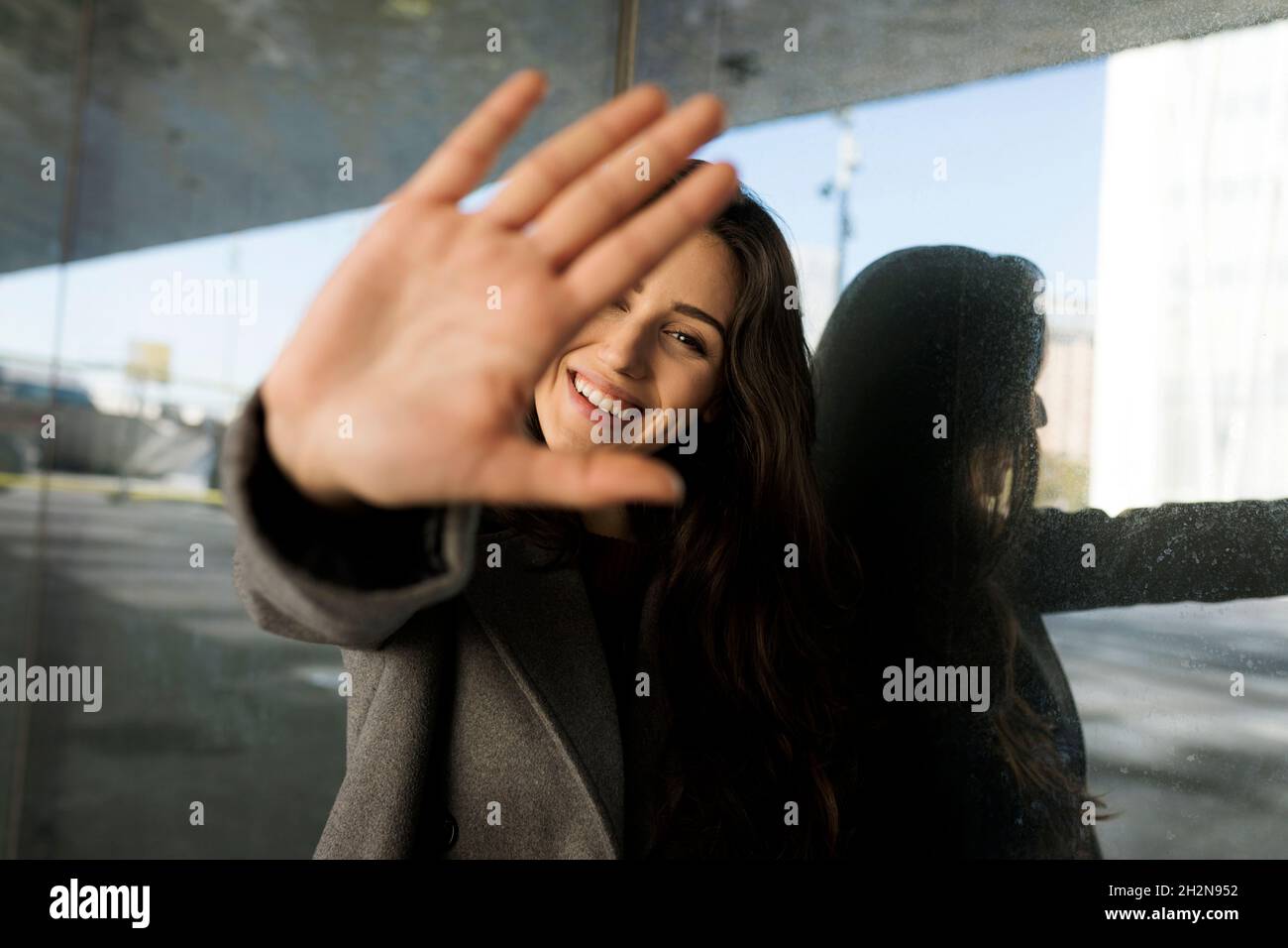 Femme montrant un panneau d'arrêt devant le mur en verre Banque D'Images