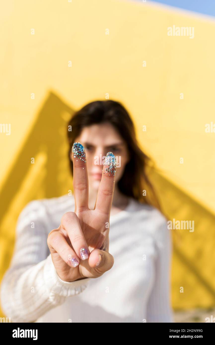 Femme signe de paix avec paillettes sur les doigts Banque D'Images