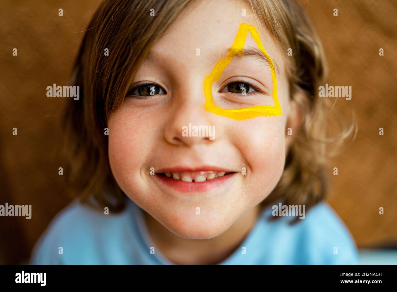 Adorable fille avec peinture jaune sur le visage Banque D'Images