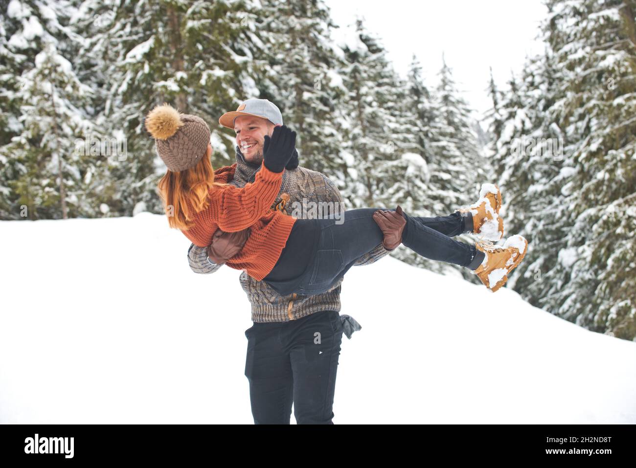 Homme et femme avec le bras autour l'un de l'autre marchant sur la neige pendant l'hiver Banque D'Images