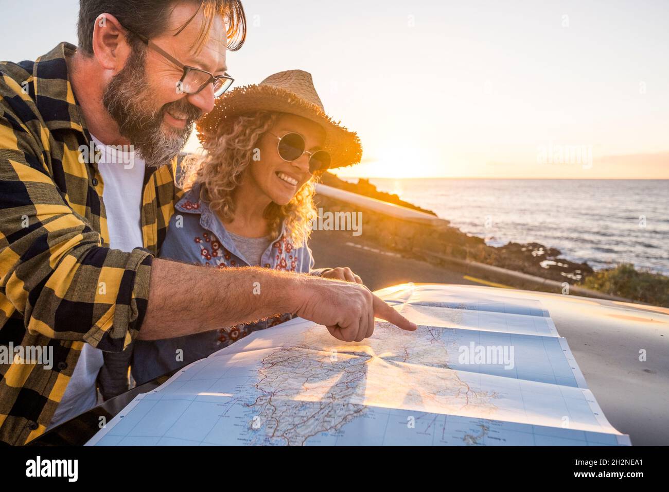 Homme souriant pointant sur la carte par une petite amie à la plage Banque D'Images