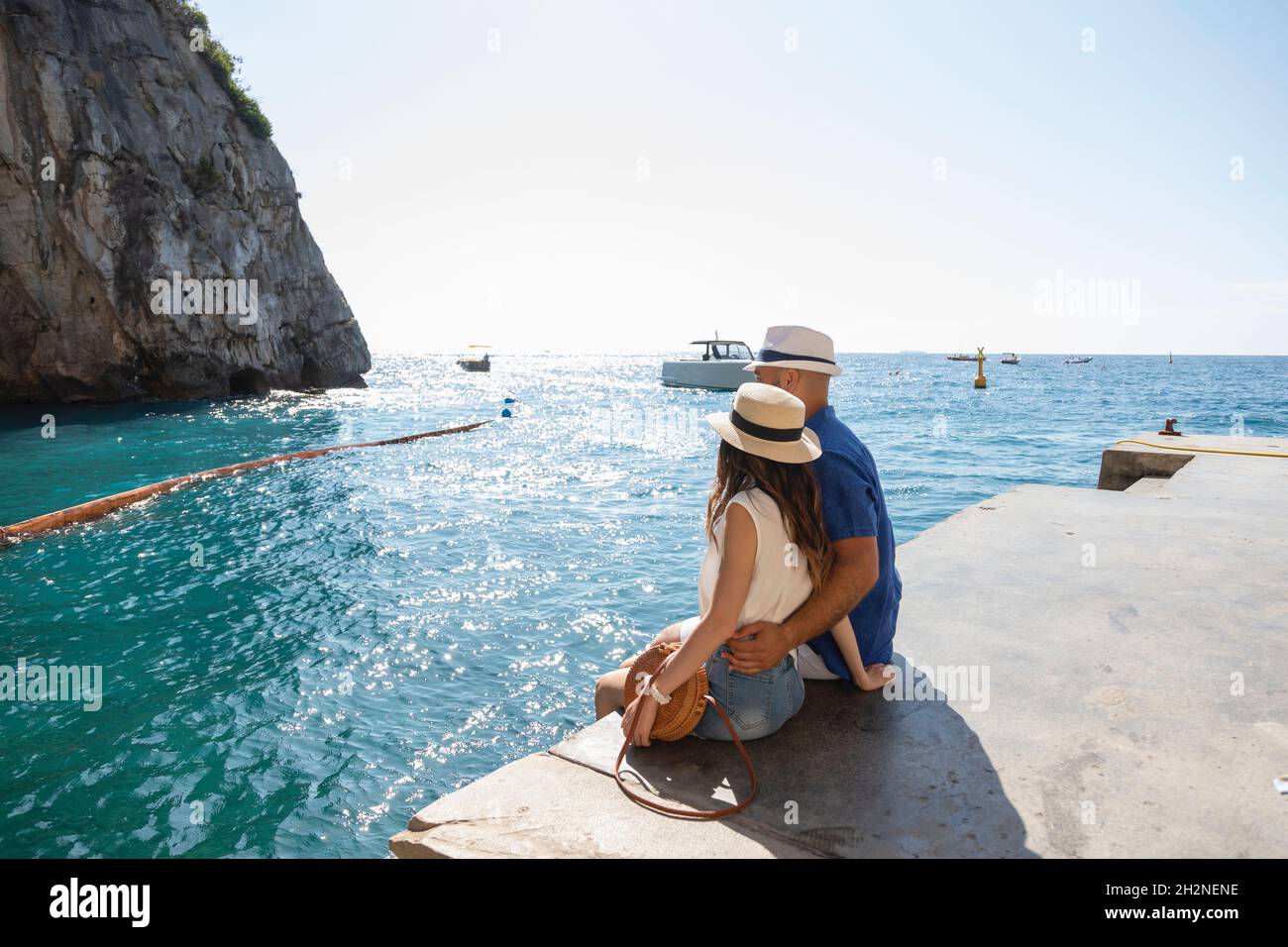 Couple adulte de taille moyenne regardant la vue sur la mer tout en étant assis sur la jetée Banque D'Images