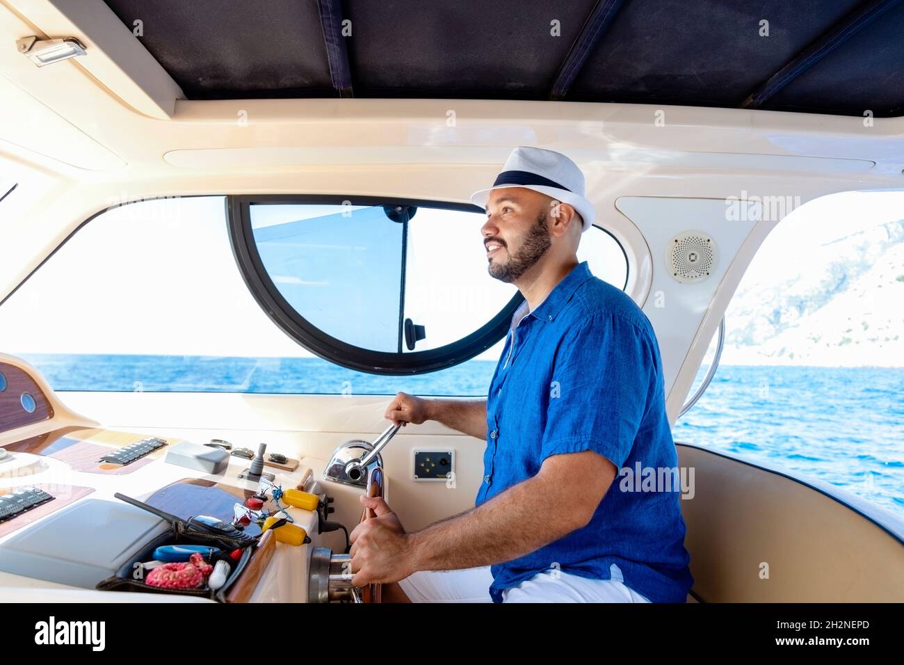 Homme portant un chapeau conduisant un bateau à moteur Banque D'Images Homme portant un chapeau conduisant un bateau à moteur Banque D'Images