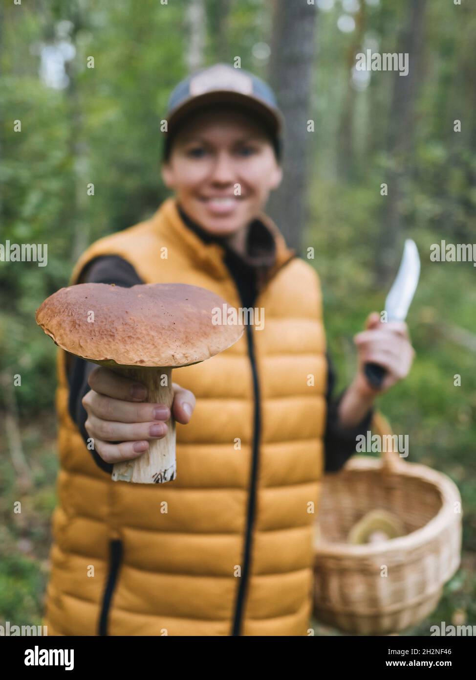 Femme souriante montrant le roi bolete champignon dans la forêt Banque D'Images