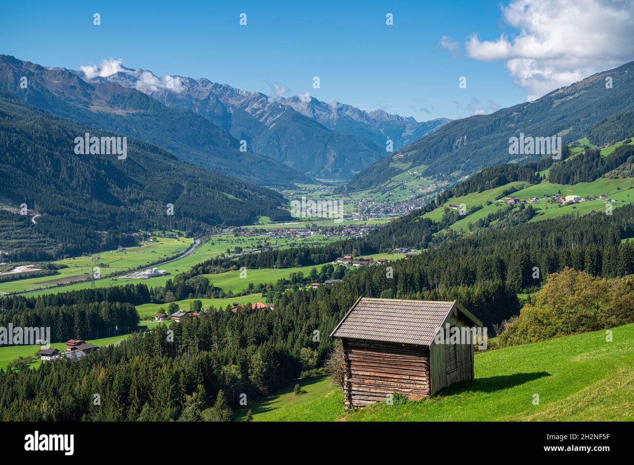 Vallée de montagne verte en été avec cabane en premier plan Banque D'Images