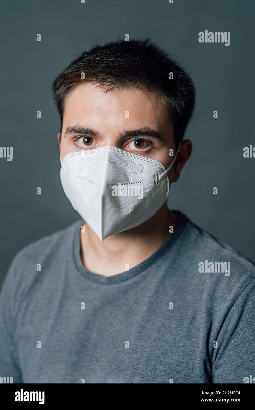 Jeune homme portant un masque de protection blanc pendant COVID-19 Banque D'Images