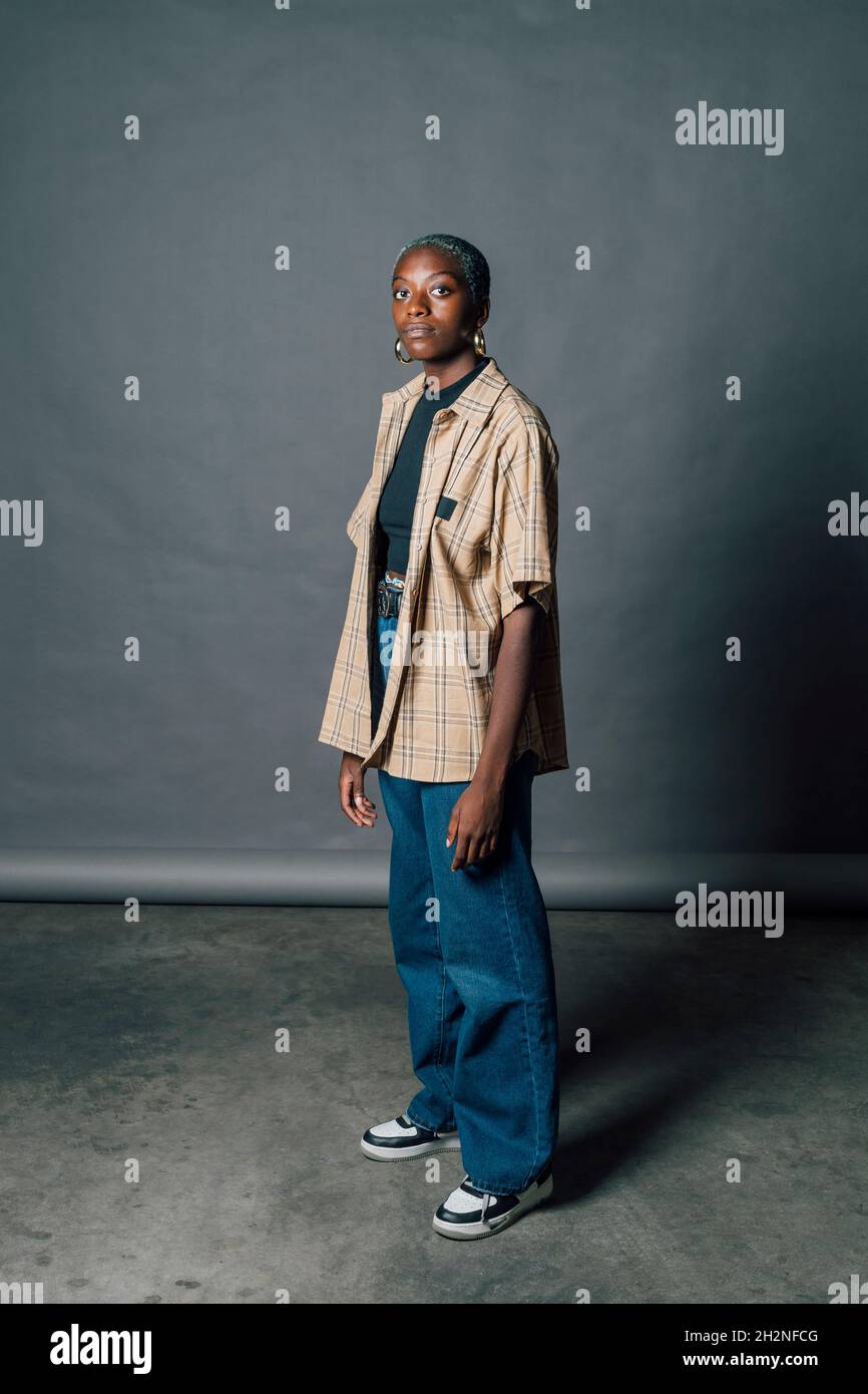 Jeune femme confiante debout en studio sur fond gris Banque D'Images