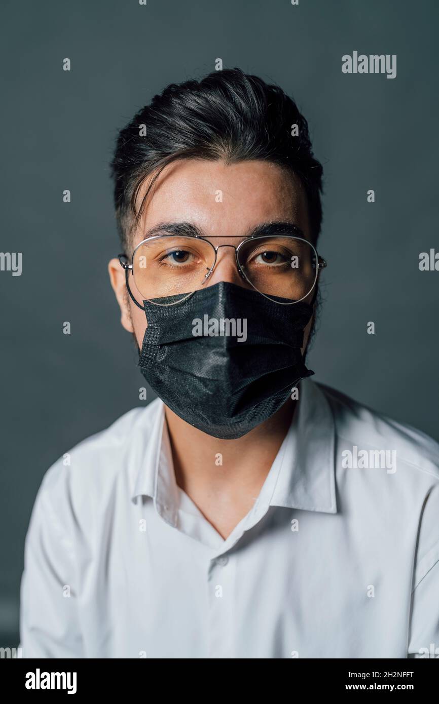 Jeune homme portant un masque de protection en studio pendant COVID-19 Banque D'Images