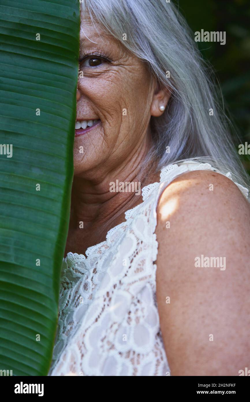 Demi-visage d'une femme âgée souriante recouverte de feuilles Banque D'Images