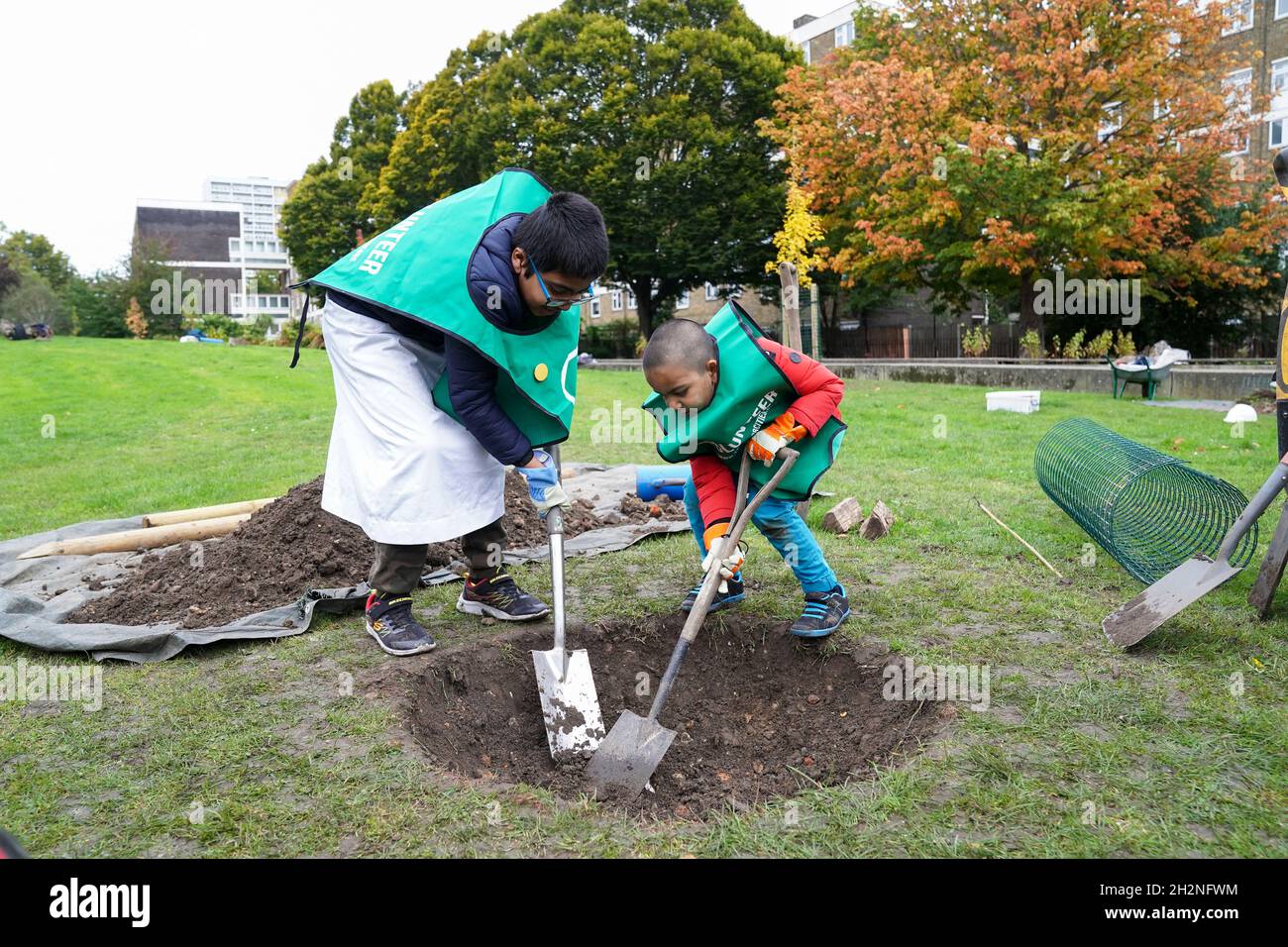 Ahmed Khan, huit ans (à gauche) et son frère Ammar Khan, quatre ans, aident à planter un arbre à Furze Green dans Tower Hamlets, à l'est de Londres, où la Reine Green Canopy dévoile son premier projet de verdissement urbain à marquer le Jubilé de platine de la Reine en 2022.Date de la photo: Samedi 23 octobre 2021. Banque D'Images